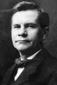 古斯塔夫(1923)黑白照片:他穿着西装，打着领结，脸上表情严肃。