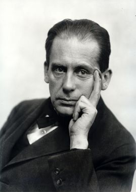 Portrait of Walter Gropius (1919) in black and white with his head resting on this hand.