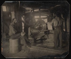 一个磨坊的内部显示三个人使用圆锯，马伯利，安大略省