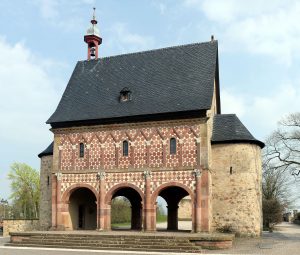 洛尔施修道院:加洛林修道院，红白砖砌，底部有三个拱门，黑色屋顶。