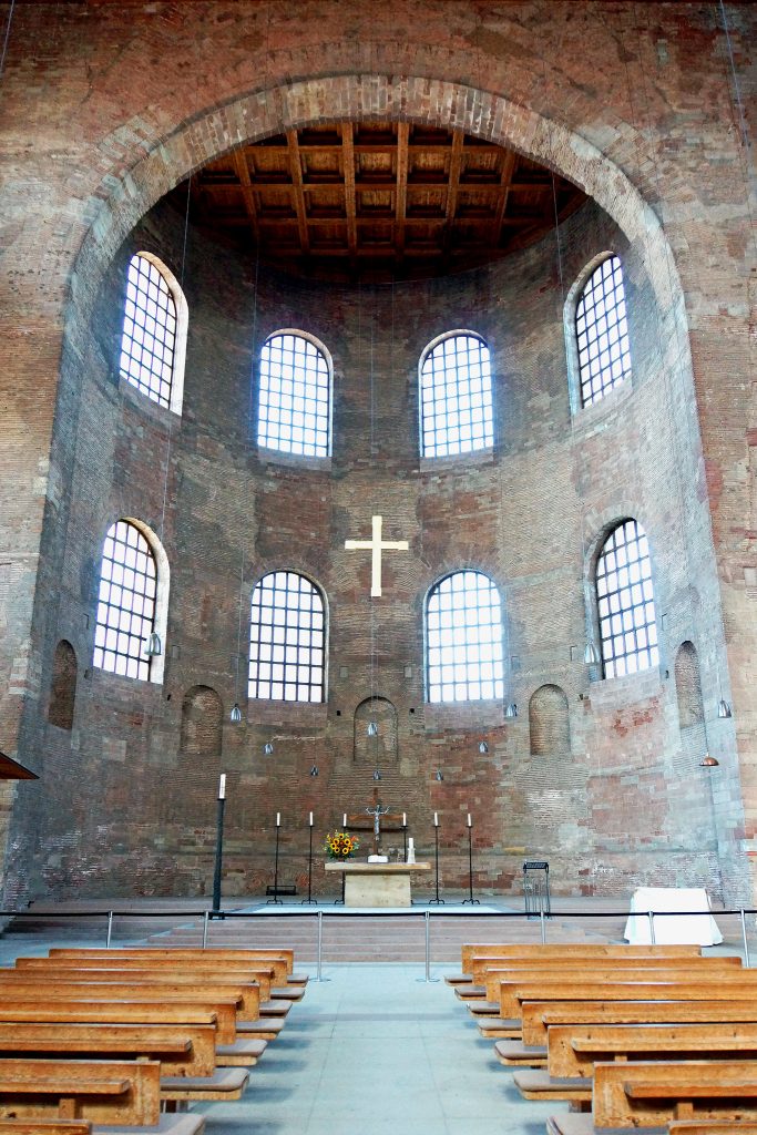 君士坦丁大教堂内部的照片。圆形圆顶结构延伸到矩形房间。照片的右下方和左侧是教堂的长凳，中间是一个小岛。又有一个坛，岛的头，坛以上有一个白十字架。