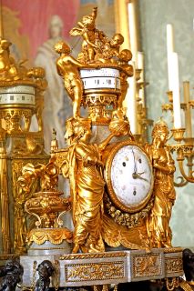 沙龙de los贵族de la雷纳性生活方式路易斯V. Un reloj de oro decorado con varios ángulos y las mujeres que rodean el reloj del cuadrante blanco.
