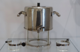 Samovar by Marianne Brandt, 1925: A silver water spout with two glasses on either side.