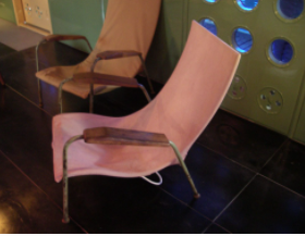 Maison Tropicale室内设计:两把弯曲的粉色椅子，扶手和腿都很细。此外，扶手是由一块细木头制成的。
