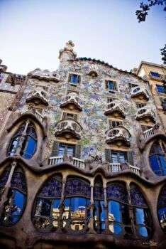 Casa Batllo, Gaudì, 1906, Barcelona: An elaborate structure with various ornate decorations along the windows.