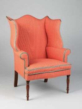 一张带有红木腿的亮橙色安乐椅。