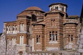 Hosios Loukas修道院:一座棕色的石头建筑，有各种细长的拱形窗户。