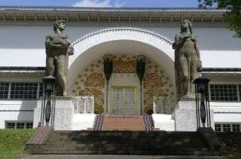 Casa迪埃内斯托Luigi Mathildenhohe,达姆施塔特:un edificio bianco con due alte statue ai lati della porta d'ingresso.