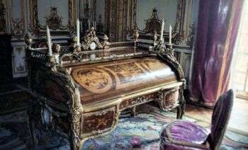 凡尔赛宫国王的桌子:一张中木质的桌子，顶部有四支蜡烛，整个桌子上有各种各样的花饰。