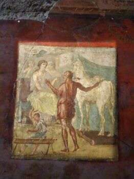 庞贝的维提之家:一幅男人背对着观众的壁画。在右下角有一匹大白马，在左上角有一个穿着白色衣服的人。在照片的左下角有第三个人在工作。