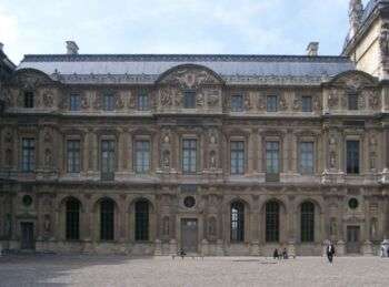 卢浮宫的莱斯科特侧翼，这是一座宏伟的棕色石头建筑，底部有一排拱门和两排窗户，顶层的窗户比中间一排小。在建筑的顶部也有一个黑色的屋顶。