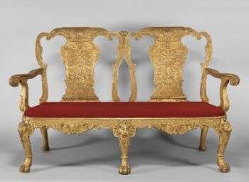胡桃木镀金石膏;以前覆盖在18世纪的红色丝绸锦缎不是原创的。一张金色双人椅，上面有红色靠垫，很可能是本杰明·古迪逊设计的。