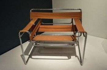 瓦西里·柴r (1925) by Marcel Breuer: A simple metal and tan-fabric chair with rectangles of fabric in stripes.