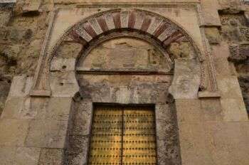 棕褐色石头清真寺里的马蹄形拱门。虽然石头的颜色正在褪色，但门是明亮的黄色。