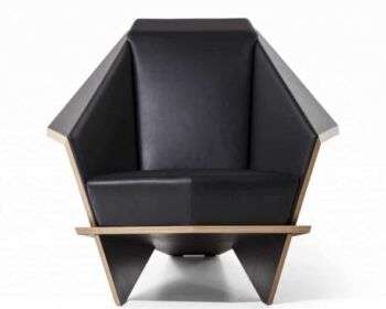 Il fronte della sedia Taliesin 1: una foto della sedia con cuscino nero e un accento di legno chiaro lungo il bordo.